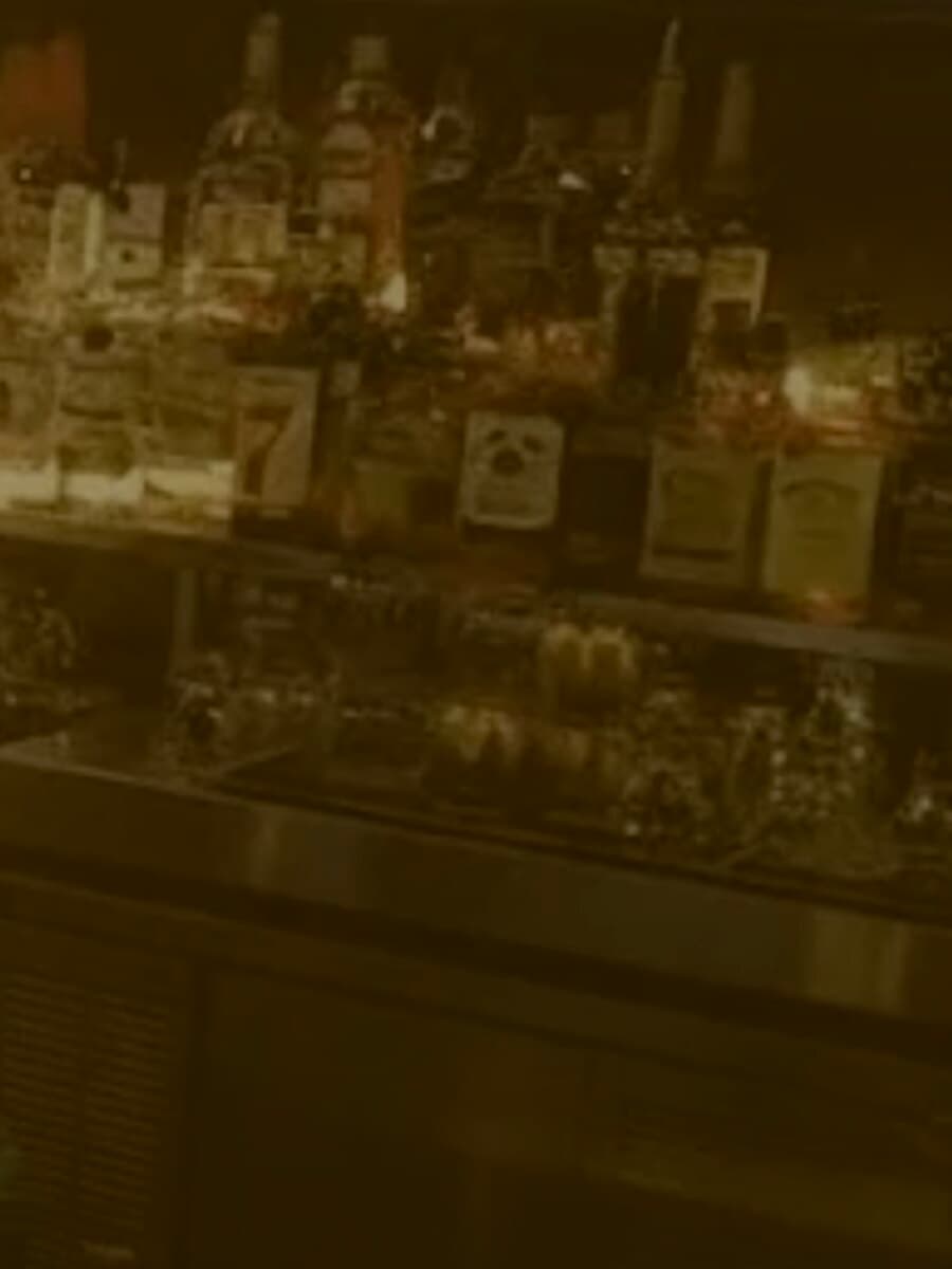 The back bar at Gra Pow Riverside, bottles lit warm against the dark